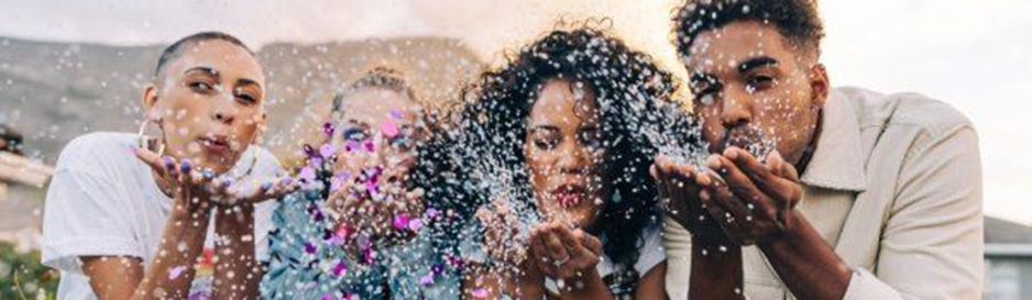 Neljä ihmistä puhaltaa käsistä strasseja